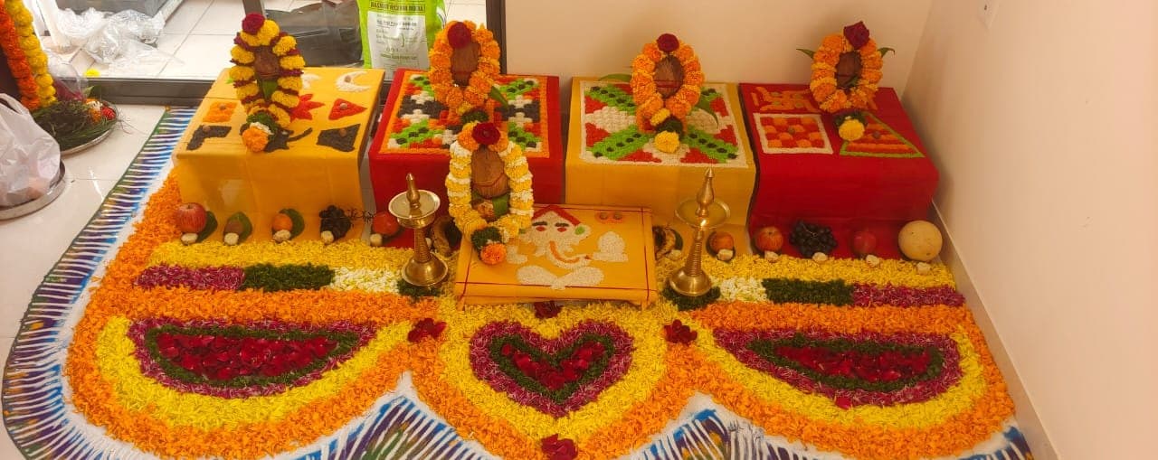 Floral rangoli laid before a decorated puja platform